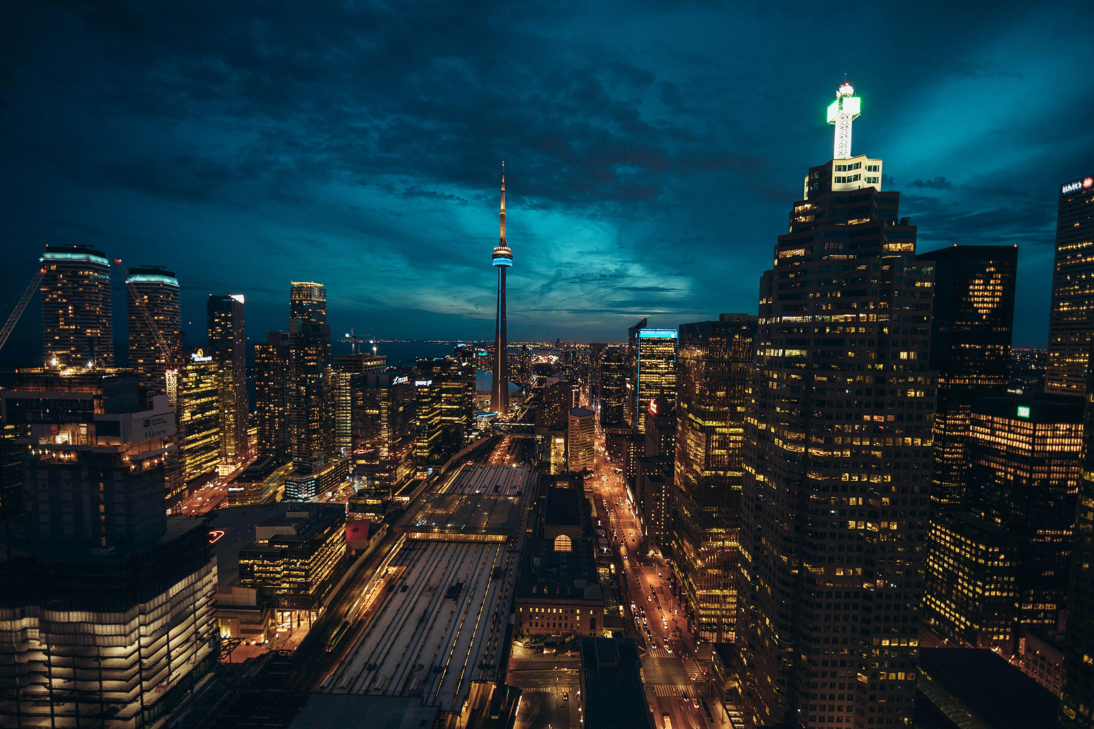 Aerial view of Toronto's vibrant city lights and CN Tower against a dark blue sky.